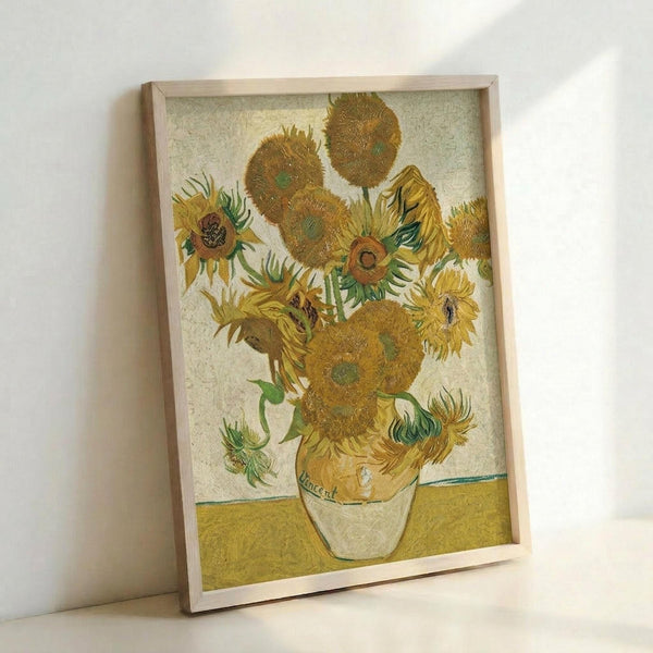 May include: Framed reproduction of Van Gogh's famous sunflowers painting leaning against white wall. The artwork shows vibrant yellow sunflowers in various stages of bloom arranged in a ceramic vase, painted in Van Gogh's distinctive thick brushstroke style with golden yellow background. Natural wood frame surrounds the textured print.