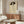 May include: Framed vintage-style line drawing of woman wearing large dark hat, displayed on wooden mid-century credenza in modern living room with white curved chair, glass coffee table, and neutral beige walls
