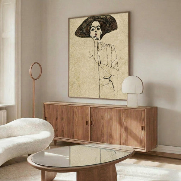 May include: Framed vintage-style line drawing of woman wearing large dark hat, displayed on wooden mid-century credenza in modern living room with white curved chair, glass coffee table, and neutral beige walls