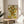 May include: Van Gogh's famous sunflowers painting reproduction in thin wooden frame, displayed on round wooden side table next to beige upholstered chair. Artwork shows vibrant yellow sunflowers in white vase against yellow surface and pale background. Warm natural lighting creates soft shadows across neutral-toned room with plant visible in corner.