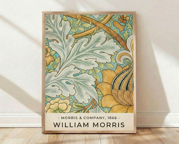 May include: Framed botanical art print featuring ornate Victorian-style design with flowing acanthus leaves in sage green and cream, golden yellow flowers, and decorative scrollwork on turquoise background. Bottom shows beige text area with Morris & Company 1866 and William Morris in black lettering. Natural wood frame sits on light wooden floor against white wall with soft fabric shadows visible.