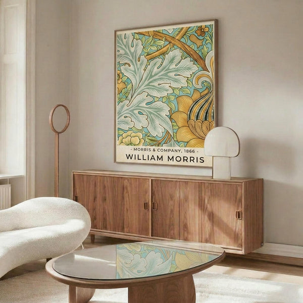 May include: Framed William Morris botanical print with sage green acanthus leaves and golden yellow flourishes displayed above a mid-century walnut credenza. Modern living room setting features cream upholstered chair, glass-top coffee table, and minimalist decor. Soft natural lighting creates warm shadows across neutral walls.