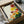 May include: Framed botanical print featuring colorful sunburst-style flowers in red, yellow, orange and pink tones with green foliage, displayed in black frame nestled in cardboard shipping box with protective tissue paper and wooden corner guards