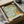 May include: Vintage botanical poster with ornate Art Nouveau floral design featuring flowing acanthus leaves in sage green, golden yellow blooms, and turquoise background, displayed in black frame inside kraft cardboard packaging with protective tissue paper wrapping on neutral surface