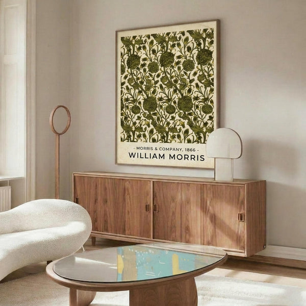 May include: Framed botanical print with green floral pattern on cream background hanging above wooden sideboard in minimalist living room. White curved chair and oval glass coffee table with colorful abstract art visible. Warm wood tones, neutral walls, and modern Scandinavian-style furniture create serene interior setting.