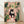 May include: Framed artwork displaying a whimsical black cat with yellow eyes sitting on a toilet reading a newspaper, surrounded by lush green houseplants including snake plants, trailing pothos, and leafy tropicals in terracotta pots. The illustration features soft pink bathroom tiles, botanical wall art, and is shown in a light wood frame leaning against a white wall on wooden flooring with natural shadows.