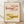 May include: Framed art print displaying two whimsical lobsters with colorful polka dot patterns in pink and yellow tones, shown in thin wooden frame leaning against white textured wall on light wooden floor with soft natural lighting and plant shadows