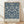 May include: Framed vintage botanical poster with intricate navy blue floral pattern on cream background, featuring symmetrical design of leaves, grapes, and ornate flowers. Wooden frame sits on light hardwood floor against white wall with soft natural lighting creating subtle shadows.