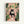 May include: Framed poster print showing a black cat with yellow eyes sitting on a toilet reading a newspaper in a pink-tiled bathroom. The room features numerous green houseplants including trailing vines, large leafed plants, and a snake plant in terracotta pots. A framed botanical print hangs on the wall. The illustration has a warm, cozy aesthetic with coral pink walls and tiles contrasting with lush greenery throughout the space.