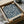 May include: Vintage William Morris botanical poster print with intricate blue floral pattern on cream background, displayed in black frame inside opened cardboard shipping box with white tissue paper protection. The detailed design features intertwining vines, flowers, and foliage in classic Arts and Crafts style.