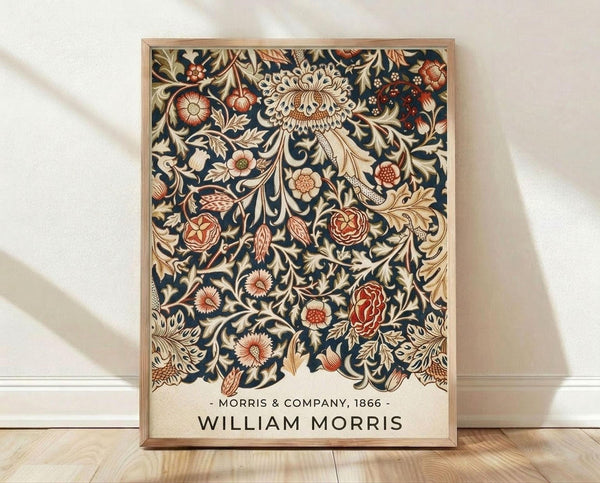 May include: Framed botanical poster with intricate William Morris floral pattern featuring red roses, cream chrysanthemums, and golden leaves on dark navy background, displayed in light wood frame against white wall on wooden floor with soft natural lighting