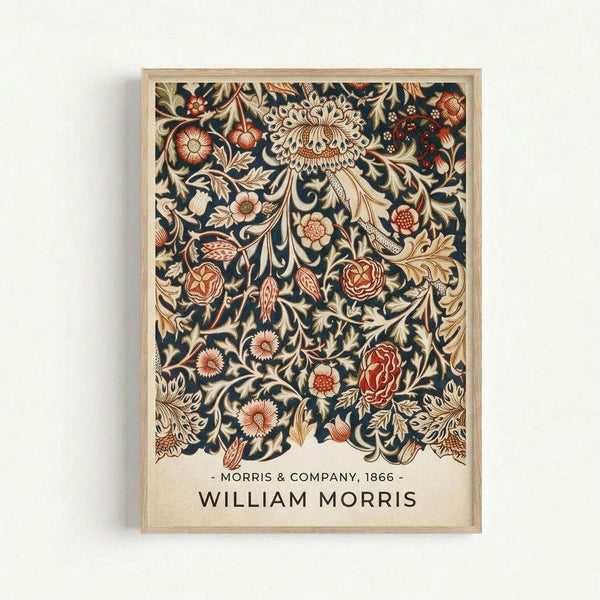 Framed vintage-style botanical print featuring intricate floral patterns with ornate blooms, leaves, and vines in rich navy blue background with coral, cream, and gold details. The design shows elaborate Victorian decorative motifs including large chrysanthemum-like flowers, roses, and flowing foliage in an all-over pattern. Text at bottom reads "Morris & Company, 1866" and "William Morris" in simple typography. Natural wood frame against white wall.