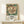 May include: Framed vintage botanical poster featuring large cream and coral peony flower with dark teal foliage, displayed on light wood console table beside white gift box. Exhibition-style poster shows William Morris-inspired floral design with Underground station reference and event details in black text below ornate bloom.