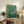May include: Framed poster print featuring a tiger swimming through turquoise waves in traditional Japanese ukiyo-e art style, displayed on a rustic wooden credenza alongside books, a ceramic vase, and fern plant in a neutral-toned living room setting with beige furniture and soft natural lighting.