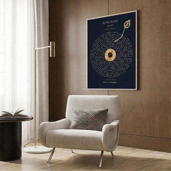 May include: Navy blue poster with gold vinyl record design and spiral text lyrics, displayed in light wood frame on wood paneled wall above cream upholstered chair with geometric pillow, brass floor lamp and dark round side table with open book nearby