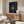 May include: Navy blue framed poster with spiral text design centered around golden vinyl record, displayed above wooden sideboard in modern living room with white curved chair, round glass coffee table, and cream colored lamp