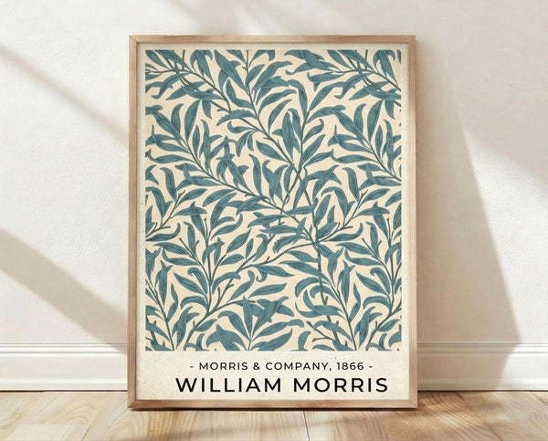 May include: Framed botanical print featuring teal blue willow branches and leaves on cream background in Arts and Crafts style, displayed in light wood frame against white textured wall on natural wood floor with soft shadows
