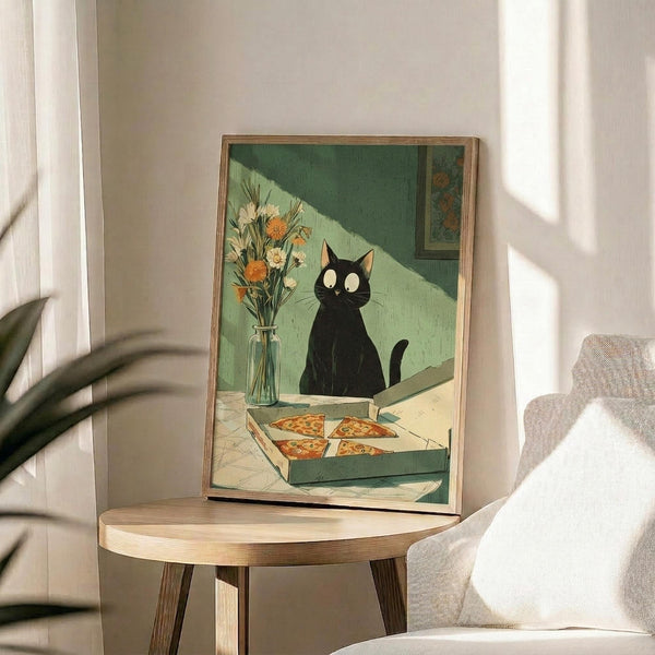 May include: Framed art print displayed on round wooden side table in bright living room with beige chair and plant. Artwork shows black cat with white eyes sitting behind open pizza box containing several slices, with flower vase on green checkered floor. Print has warm green and cream tones in thin natural wood frame.