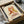 May include: Framed poster artwork showing abstract line drawing of dancing couple in warm coral, orange and yellow tones above detailed turntable illustration. Black frame sits in cardboard shipping box with tissue paper and cardboard tubes on white surface.