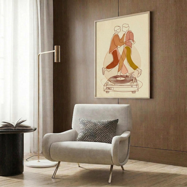 May include: Modern living room scene showing framed poster on wood paneled wall featuring two dancing figures in orange and yellow clothing above a vintage turntable, illustrated in minimalist line art style. Cream-colored armchair with geometric pillow, brass floor lamp, and dark round side table with open book complete the contemporary interior setting.