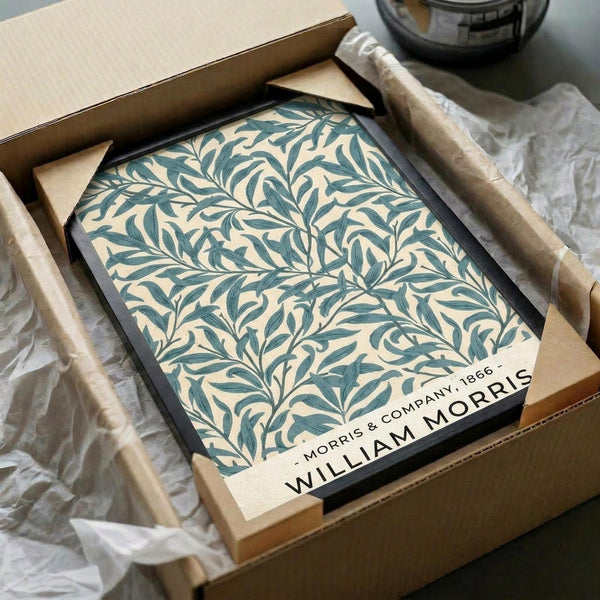 May include: Framed botanical poster with teal and cream willow branch pattern in black frame, nestled in cardboard box with tissue paper packaging. Art print features flowing organic leaf design in William Morris style, surrounded by shipping materials on white surface.