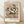 May include: Framed art print of Van Gogh's white roses in a yellow vase against pink diagonal brushstroke background, displayed in light wood frame leaning against white wall on wooden floor with soft natural lighting and fabric shadows