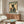 May include: Framed vintage-style poster on beige wall above wooden sideboard featuring black cat in traditional Japanese clothing holding red cup, with "MORE ESPRESSO LESS DEPRESSO" text. Modern living room setting with cream curved chair, glass coffee table, and warm wood furniture in natural lighting.