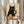May include: Person holding framed poster print showing black cat with white eyes sitting at wooden table, holding wine glass with red wine, surrounded by various cheese wedges. Artwork has vintage cream background with light wooden frame. Dried pampas grass visible on left side of scene.