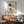 May include: Framed Kandinsky abstract art print with geometric shapes, circles, and lines in black, red, and neutral tones, displayed above a mid-century modern wooden credenza with table lamp. Green upholstered armchair with wooden frame sits nearby on hardwood floor. Natural sunlight creates dramatic shadows on white wall in minimalist living room setting.