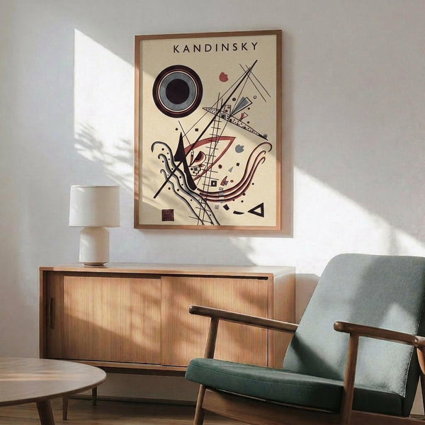 May include: Framed Kandinsky abstract art print with geometric shapes, circles, and lines in black, red, and neutral tones, displayed above a mid-century modern wooden credenza with table lamp. Green upholstered armchair with wooden frame sits nearby on hardwood floor. Natural sunlight creates dramatic shadows on white wall in minimalist living room setting.
