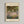 May include: Framed poster print of Claude Monet's impressionist garden painting featuring vibrant purple and pink flowers in foreground with lush green foliage and trees creating a canopy overhead. The artwork shows Monet's signature loose brushwork and bright color palette. Natural wood frame with cream matting displays the print on a light gray wall.