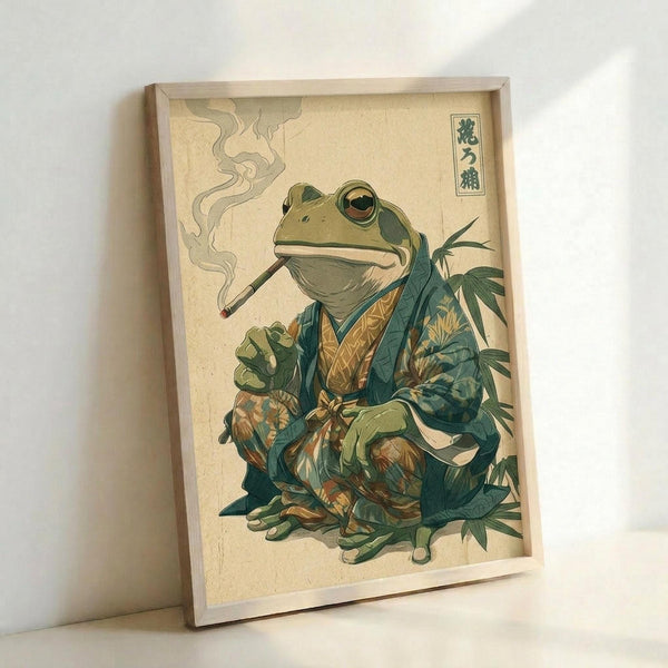 May include: Framed art print leaning against white wall showing anthropomorphic green frog wearing traditional Japanese kimono with teal and gold patterns, smoking a long pipe with wisps of smoke rising. The frog sits among leafy plants in classic Japanese woodblock print style on cream background with Japanese characters in upper right corner. Natural wood frame visible.
