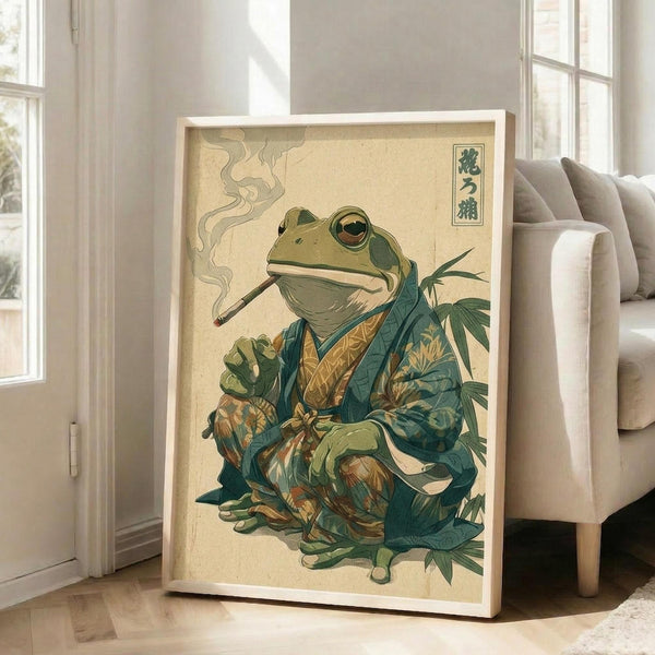 May include: Framed poster print leaning against white wall next to beige sofa in bright living room. Artwork shows anthropomorphic green frog in traditional Japanese kimono with teal and gold patterns, smoking a long pipe with visible smoke wisps. Frog sits cross-legged among green foliage against cream background in vintage Japanese woodblock print style. Japanese characters visible in top right corner. White wooden frame, approximately 2-3 feet tall.