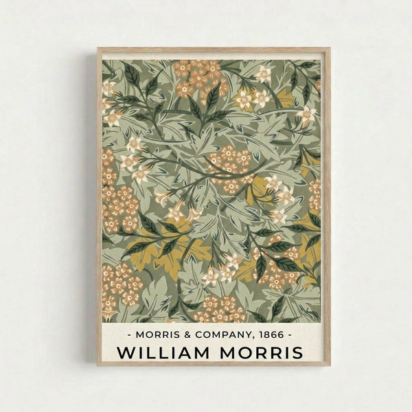 Vintage botanical wallpaper pattern featuring intricate green foliage, orange and coral flowers, and yellow leaves on a sage green background. The decorative design is displayed in a light wooden frame against a white wall, with text below reading "Morris & Company, 1866" and "William Morris" in black lettering.