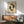 May include: Framed poster featuring two black koi fish in circular swimming pattern on aged beige background with red Chinese characters and "LOSE YOUR MIND, FIND YOUR SOUL" text below. Displayed above wood credenza with white ceramic lamp in modern living room setting with sage green mid-century armchair and natural sunlight casting shadows on white wall.