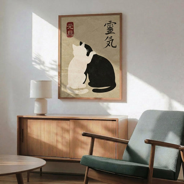 May include: Framed poster featuring two cats in yin-yang pose - one white, one black - on beige textured background with Japanese characters and red seal stamp. Displayed above mid-century modern wooden credenza with ceramic table lamp in minimalist living room setting with sage green upholstered chair and round coffee table.