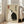 May include: Framed poster with beige textured background featuring two cats - one white, one black - sitting back-to-back in yin yang formation. Red seal and black Japanese characters in upper corners. Light wood frame displayed on floor against white walls near beige upholstered chair and windows with natural lighting.