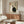 May include: Minimalist Japanese-style poster featuring black and white yin-yang cats with Asian characters and red seal stamp, displayed above a walnut wood credenza in modern living room with white sculptural chair, glass coffee table, and brass floor lamp