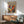 a vibrant abstract painting hanging on a wall above a wooden cabinet, with a green armchair and a round wooden table in the foreground.