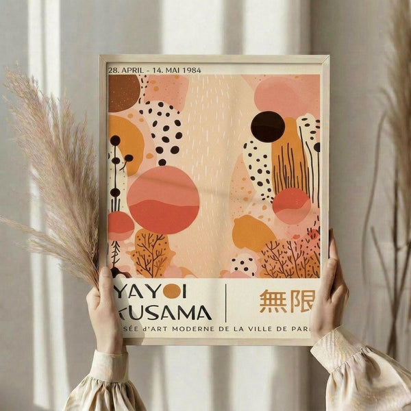 A person is holding up a framed poster with a colorful abstract design featuring various shapes and patterns.