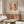 a modern living room with a large abstract art poster on the wall, a wooden cabinet, a white sofa, and a glass coffee table.