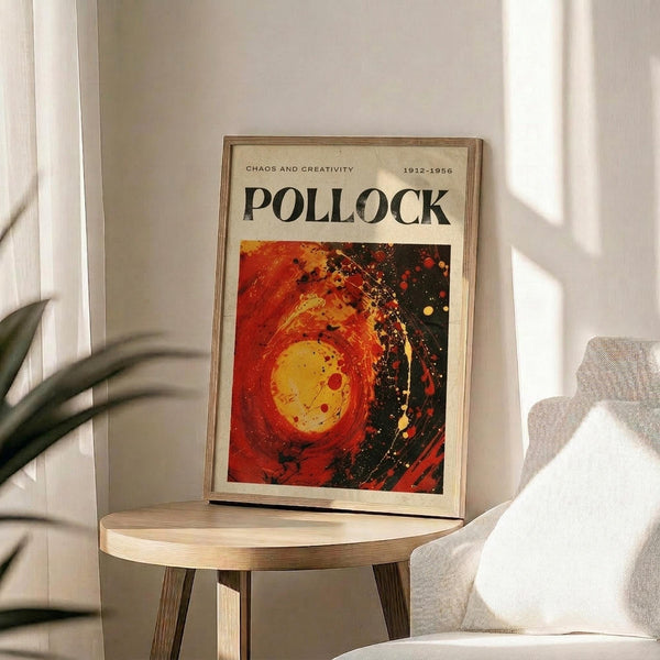 a framed poster of Pollock's artwork, which is displayed on a wooden table in a room with a white chair and a plant in the background.