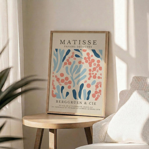a framed poster of the Métisse art movement, with a floral pattern in shades of blue, pink, and orange. The poster is displayed on a wooden table, and there is a white couch in the background.
