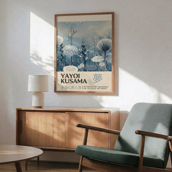a living room with a framed poster of a floral design hanging on the wall, a wooden cabinet, a green armchair, and a round wooden table.