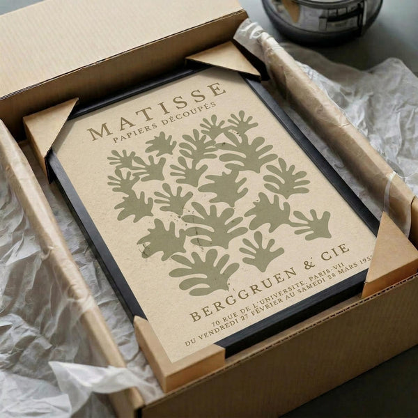 a framed poster of the Matisse artwork "Papiers d'acoupe" (Paper Art) displayed in a cardboard box.