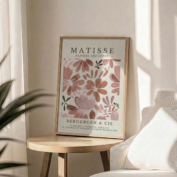a framed poster of a floral pattern on a wall, with a wooden table in the foreground and a white couch in the background.