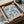 a framed poster of a blue floral design, which appears to be a piece of artwork. The poster is placed in a cardboard box, and there is some wrapping paper visible around it.