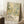 A framed poster of Yayoi Kusama's work displayed on a wall, with a cup of coffee and a wooden stool in the foreground.