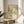 A framed poster of a floral design hangs on a wall in a room with a wooden table and a white chair.