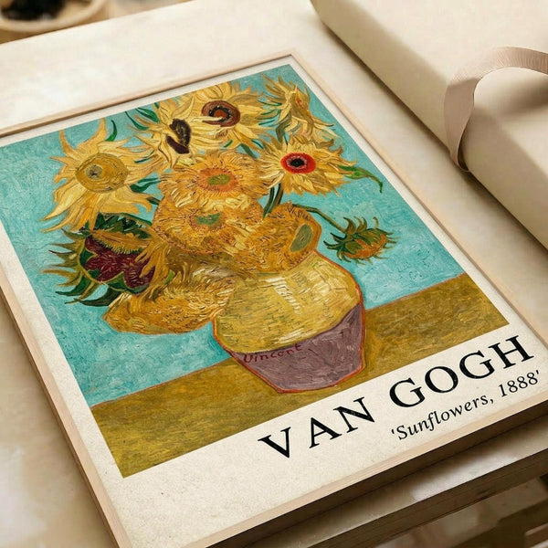 May include: Van Gogh's Sunflowers reproduction print displayed on white paper with cream ribbon nearby. The artwork shows vibrant yellow sunflowers in a ceramic vase against turquoise and olive green background. Print features white border with "VAN GOGH" and "Sunflowers, 1888" text at bottom. Visible brushstroke texture and warm golden tones throughout the classic Post-Impressionist painting reproduction.